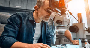 Man looking through microscopes in an industrial setting